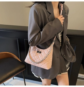 Détail du sac seau rose matelassé avec chaîne argentée porté par un mannequin