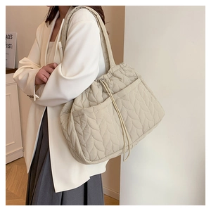 Detail of beige quilted tote bag showing cloud-like texture and drawstring closure