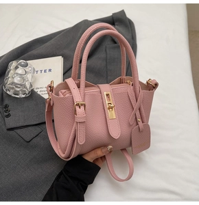 Detail of pink lychee leather bucket bag with gold twist-lock and matching leather tag