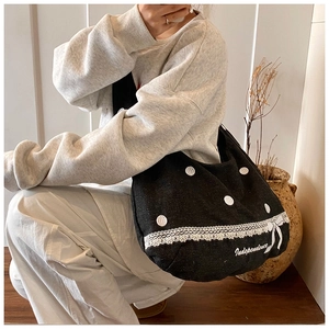 Détail d'un sac cabas en toile noir avec pois blancs, dentelle et nœud décoratif
