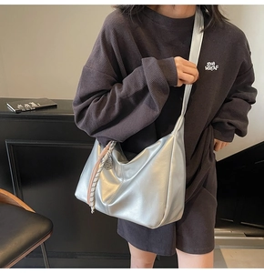 Detail of silver metallic hobo bag featuring soft texture and woven rope charm accents