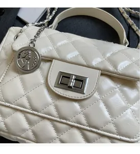 Detail of cream quilted bag with silver twist lock and portrait coin charm