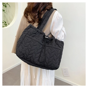 Detail view of the black quilted tote bag with leaf texture and drawstring closure