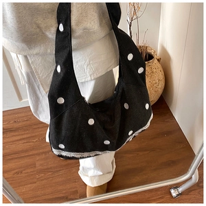 Détail du sac cabas en toile noir avec broderie à pois blancs et bordure en dentelle chic