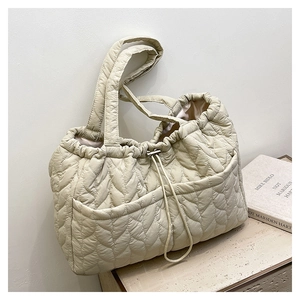 Close-up of beige quilted tote bag showing leaf pattern texture and drawstring closure