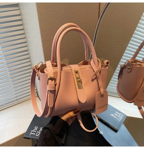 Close-up of pink lychee grain leather bucket bag with gold hardware and adjustable strap