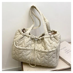 Detail of light beige quilted tote bag featuring wave stitching and dual front pockets