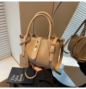Close-up of beige lychee-pattern leather bag with golden twist-lock and fine stitching