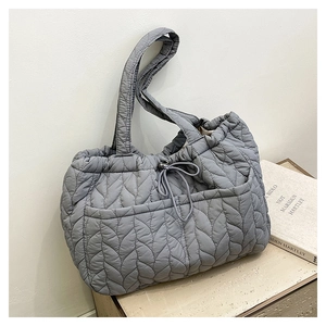 Macro shot of grey quilted tote bag with wheat pattern stitching and drawstring closure