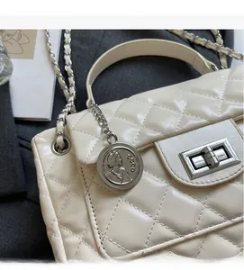 Close-up of quilted cream leather texture with silver metal clasp and coin charm detail