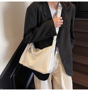 Detail of cream-colored large hobo bag with soft leather texture and braided pendant