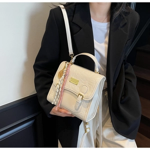 Détail du sac en similicuir crème avec motifs de dessins animés et foulard en soie