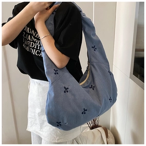 Détail du sac cabas en denim bleu clair avec motifs cerises brodés et style hobo