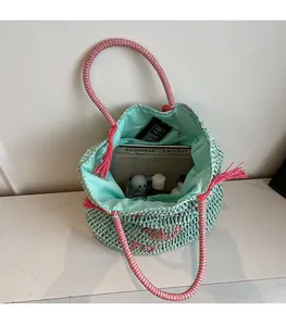 Detail view of mint green straw tote bag showing spacious interior with blue lining and zip pocket