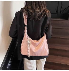 Detailed back view of a pink hobo shoulder bag with a wide strap on a wooden staircase