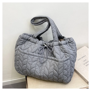 Detailed close-up of dark grey quilted fabric texture and stitching on the tote bag