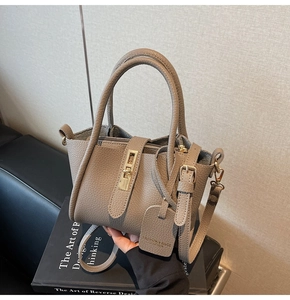 Detail of taupe pebbled leather bucket bag with gold hardware and fashion tag