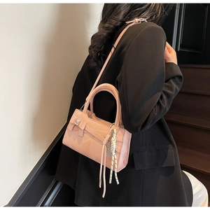 Dettaglio di borsa rosa con fiocco e ciondolo a nappa su un blazer nero elegante