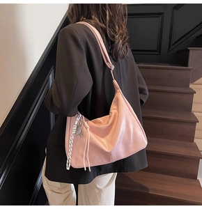 Pink hobo bag with adjustable strap and silk scarf detail shown on street model