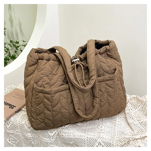 Close-up of brown quilted tote bag showing wavy stitching and spacious side pocket