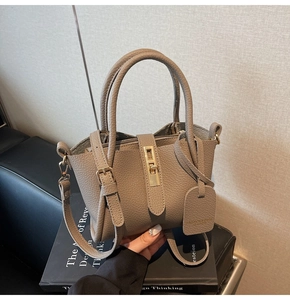 Detail of grey lychee leather bucket bag with gold turn-lock and adjustable strap
