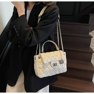 Quilted cream crossbody bag with silver chain strap worn by model in formal outfit