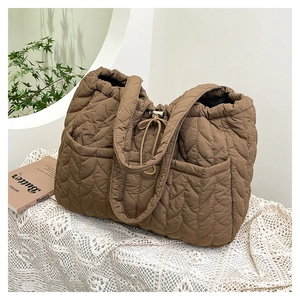 Detailed scene of brown quilted tote bag with heart patterns on a lace table