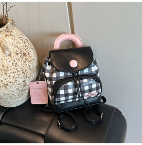 Detail of checkered mini backpack with pink handle and transparent card holder tag