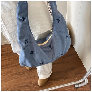 Détail d'un sac cabas en toile bleue avec cerises brodées et fermeture éclair
