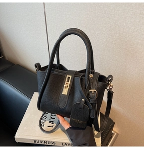 Close-up of black lychee leather bucket bag with gold hardware and leather hangtag detail