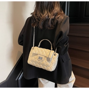 Detail of cream quilted chain bag featuring glossy finish and elegant metal twist lock