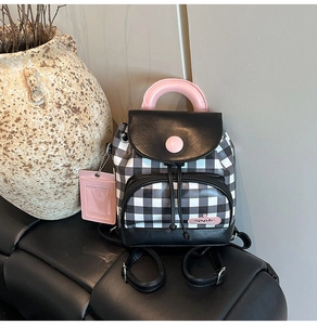 Mini checkered backpack with leather trim and pink handle details shown in a lifestyle setup