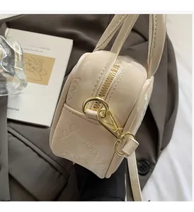 Detail der cremefarbenen Tasche mit Schmetterlingsprägung und goldenen Metallakzenten