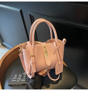 Detailed shot of pink lychee leather bucket bag with gold lock and adjustable strap