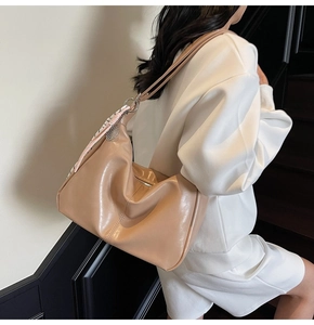 Detail of light brown crescent shoulder bag with soft leather texture and silk scarf