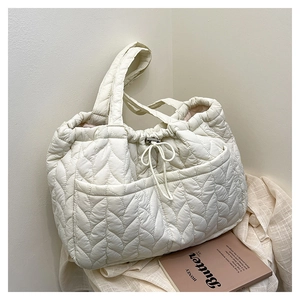Close-up of white quilted tote bag featuring wave stitching and adjustable drawstring closure