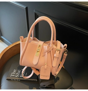 Detail of pink lychee leather bucket bag with gold twist lock and designer hangtag