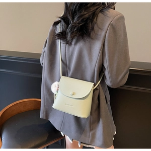 Detail view of mint green pebble leather crossbody bucket bag on a model wearing a grey blazer