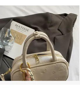 Detail der cremefarbenen Bowlingtasche mit 3D-Prägung und goldenen Reißverschlussbeschlägen