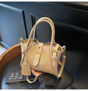Detailed macro view of beige pebble leather bucket bag featuring gold metal hardware lock