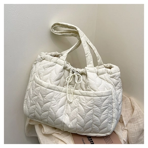 Detail shot of leaf-patterned quilted tote bag with drawstring and front pockets