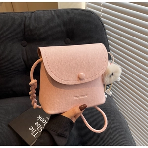 Pink lychee grain leather bucket bag with braided strap and plush monster charm detail