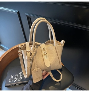Close-up of beige lychee texture bucket bag with gold swivel lock and leather tag