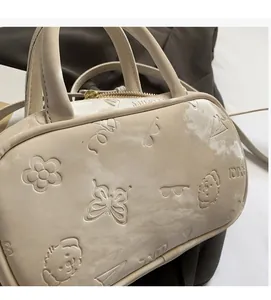 Details von geprägten Schmetterlings- und Cartoon-Mustern auf cremeweißem Leder der Tasche
