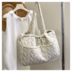 Close-up of white quilted tote bag featuring leaf-pattern stitching and side drawstrings