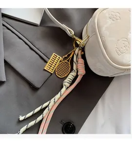 Nahaufnahme eines stilvollen Gold-Abakus und Tennisschläger Taschenanhängers mit Quaste