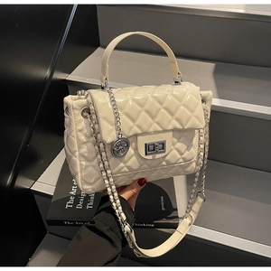 Close-up of quilted rhombic pattern, gold chain strap, and metallic lock on cream bag