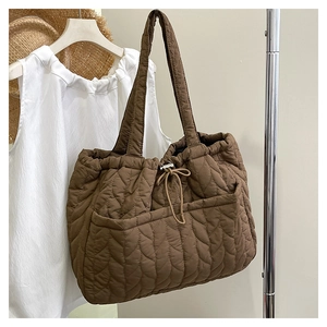 Detail of brown quilted puffer tote bag featuring drawstring closure and textured nylon fabric