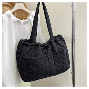 Detail of black quilted tote bag featuring wavy stitching and adjustable drawstring closure