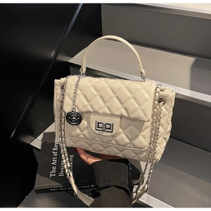 Close-up of cream quilted crossbody bag featuring silver turn-lock and chain strap